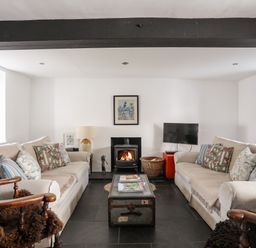 A living room with two beige sofas a wood stove and a television at Bryn Tegid in Beaumaris