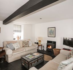 A living room with two beige sofas a wooden armchair a coffee table and a fireplace at Bryn Tegid in Beaumaris