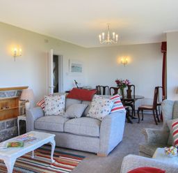 A living room with sofas cushions a coffee table and a dining table with chairs at Camlan in Beaumaris