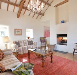 A living room with a fireplace two couches wooden chairs a chandelier and a coffee table at Cefn Isaf in Porthmadog
