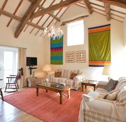 A living room with wooden beams on the ceiling sofas a coffee table and a red rug at Cefn Isaf in Porthmadog