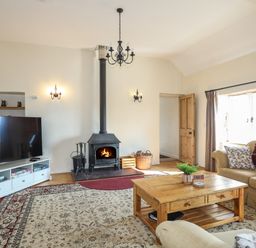 A living room with a fireplace sofa coffee table and television at Tan Twr - Chellow Cottage in Dwyran