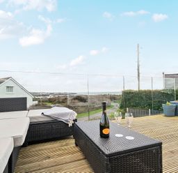 An outdoor space with seating and a bottle of wine at Curragho in Trearddur Bay