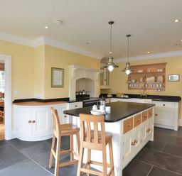 A kitchen with island and wooden stools and hanging lights at Dinas Noddfa in Nant Gwynant