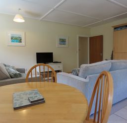A living room with a sofa and television at Bryn Eira Tack Room in Llanfair PG