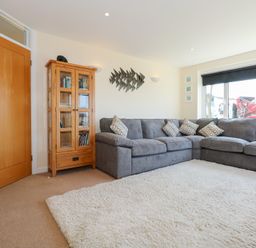 A living room with a grey sectional sofa and a wooden cabinet at Flip Flops in Rhosneigr