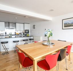 A kitchen with a dining table and red and black chairs four The Quay in Red Wharf Bay