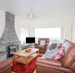 A living room with brown leather sofas a stone fireplace a wooden coffee table and a television at Frondeg in Rhiwlas
