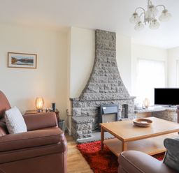 A living room with leather armchairs a stone fireplace wooden coffee table and a television at Frondeg in Rhiwlas