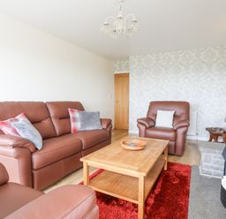 A living room with brown leather sofas wooden coffee table and stone fireplace at Frondeg in Rhiwlas