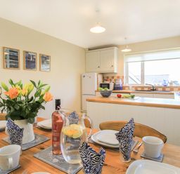 A kitchen and dining area with a set table and flowers on the table at Garnedd Lwyd in Llanfair
