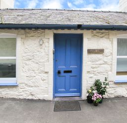 The exterior of a building with a blue door two windows and potted plants on the ground at Glan Dwr Bach in Glyn Garth