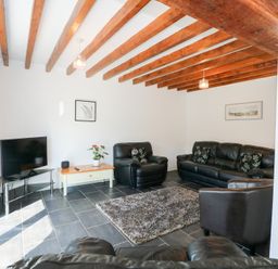 A living room with leather sofas a television and wooden ceiling beams at Hafod in Pontllyfni