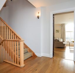 A wooden staircase with carpeted steps next to an open door leading to a living room at Harlech Apartments - Bendigeidfran in Harlech