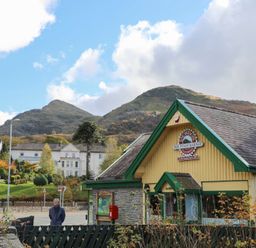 A railway station building with snowdon mountain railway sign and mountains in the background at Hirfron in Llanberis