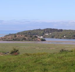 A landscape with grassy fields water and trees at Big House in Llandecwyn
