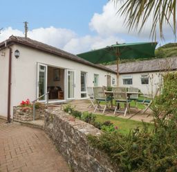An outdoor area with a table and chairs under an umbrella at Menai Cottage in Brynsiencyn