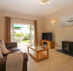 A living room with a sofa, tv, and coffee table at Menai Cottage in Brynsiencyn