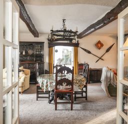 A dining room with a wooden table and chairs a cabinet and yellow curtains at Morfa Lodge in Porthmadog