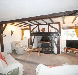 A living room with wooden beams a fireplace sofas and a television at Morfa Lodge in Porthmadog