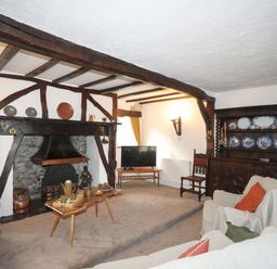 A living room with a fireplace wooden beams wooden furniture and a television at Morfa Lodge in Porthmadog