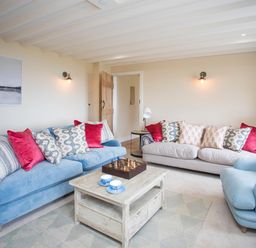 A living room with two sofas an armchair a wooden coffee table with a chess set and cups and a wooden door at Penrhyn Barn in Dulas