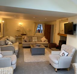 A living room with sofas armchairs a coffee table a wall-mounted TV and a fireplace at Penrhyn Farm Moelfre