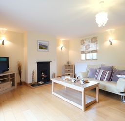 A living room with a sofa coffee table television and fireplace at Pen Y Bont in Pontllyfni