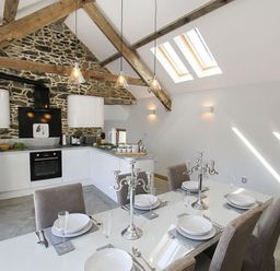 A kitchen and dining area with stone wall and wooden beams at Rhyd Angharad Barns in Rhydwyn