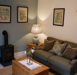 A living room with a sofa and artwork on the wall at The Honey Pot in Garndolbenmaen