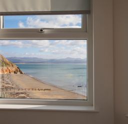 A window showing a beach with a cliff and calm sea at The Towers - Ardudwy in Criccieth