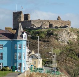 A street with houses and a stone castle on a hill at The Towers - Castell in Criccieth