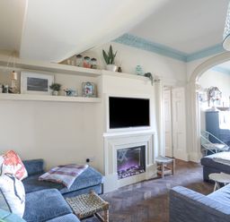 A living room with blue sofas a fireplace and a television above it at Towyn Lodge in Trearddur Bay