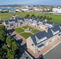 A courtyard with a fountain surrounded by stone buildings in a rural area at Tyn Towyn - Bwthyn Haf in Trearddur Bay