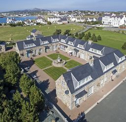An aerial view of a U shaped stone building with a central courtyard and green lawn at Tyn Towyn - Ty Oren in Trearddur Bay