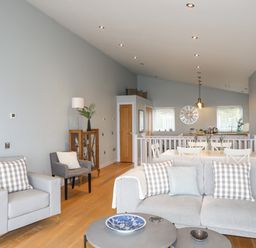 A living room with sofas and a dining area with wooden doors at Ty Glyn in Criccieth