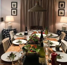 A dining room with a wooden table set with plates glasses bottles and salad bowls with chairs around at Ty Mawr Porthmadog in Porthmadog