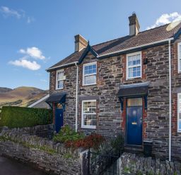 Stone terraced houses with blue doors and window frames in a rural area with hills in the background at 17 Victoria Terrace  Perthi in Nantlle