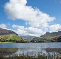 A lake surrounded by green hills under a blue sky with clouds at 17 Victoria Terrace - Perthi in Nantlle