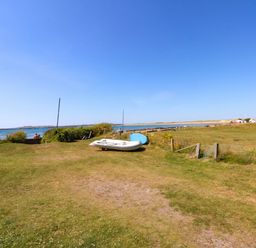 A view of the sea with boats and grass at Windygates in Rhosneigr