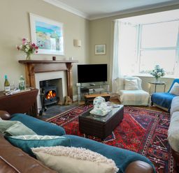 A living room with a fireplace and television at West View in Rhosneigr