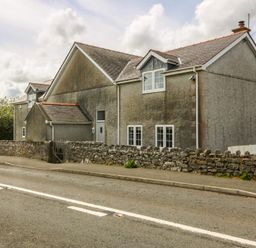 A house with windows and a fence on the roadside at Llanallgo Church Rooms