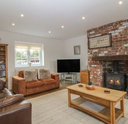 A living room with a fireplace and sofa at Llanallgo Church Rooms
