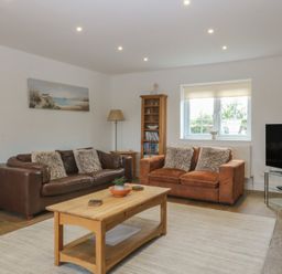 A living room with sofas, a coffee table, and a television at Llanallgo Church Rooms in 