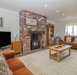 A living room with a sofa, fireplace, and TV at Llanallgo Church Rooms