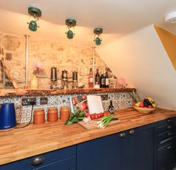 A kitchen countertop with a blue kettle jars vegetables bottles and a fruit bowl at Bonny Bits Cottage in Garrigill near Alston