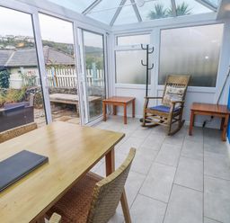 A conservatory with a table and chairs at Pebble Cottage Portreath