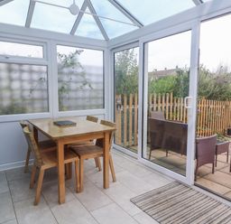 A conservatory with a table and chairs at Pebble Cottage in Portreath
