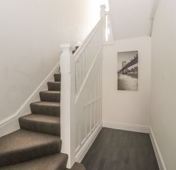 A carpeted staircase with white banister and a black and white photo on the wall at Sea Breeze in Rhos-on-Sea