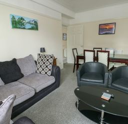 A living room with a sofa and dining area at Sea Breeze Rhos-on-Sea